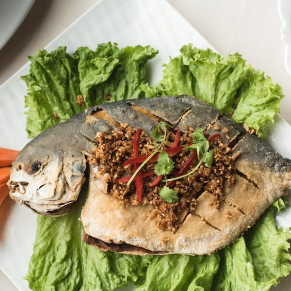 Whole fried fish, garnished with minced garlic, red chili, and cilantro, served on lettuce.