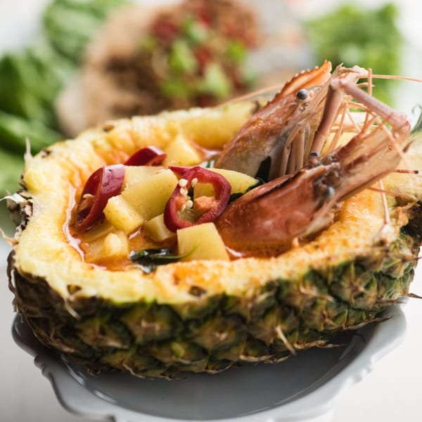 Thai pineapple curry with shrimp, red peppers, and pineapple chunks, served in a carved pineapple.